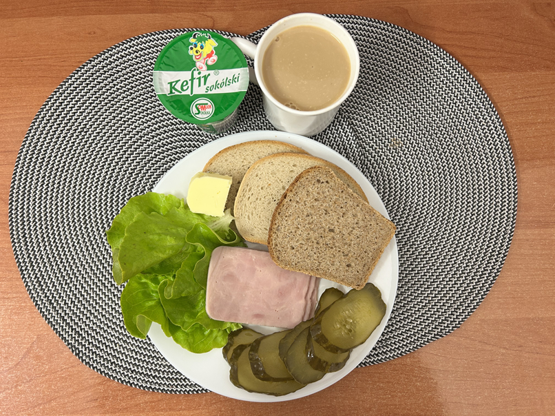 Na zdjęciu: Kefir 2%,Kawa zbożowa z mlekiem, Chleb mieszany pszenno-żytni, Chleb Graham, Masło extra 82%, Szynka Premium konserwowa, wieprzowa, parzona z poł. kaw. mięsa, Ogórek kiszony, Sałata zielona